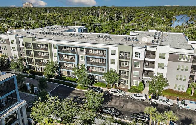 an aerial view of a large apartment building with cars parked outside