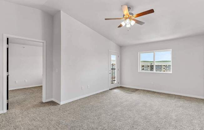 A room with a ceiling fan and a window overlooking a beach.