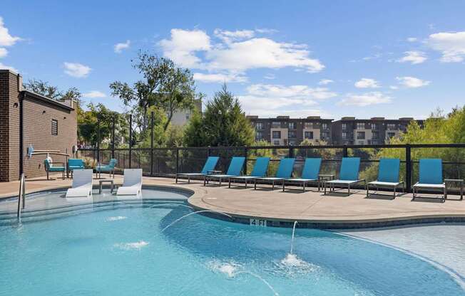 A swimming pool with a waterfall and lounge chairs.