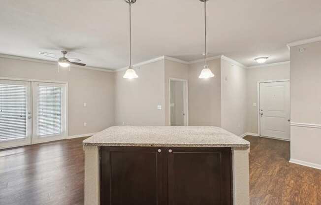 an empty kitchen with a counter top and a door to a living room