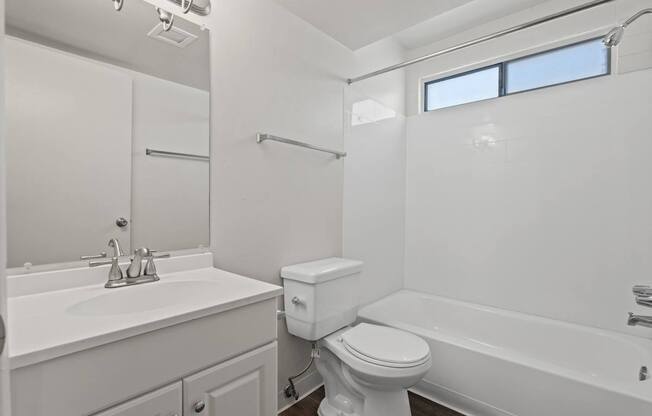 A white bathroom with a toilet, sink, and bathtub.