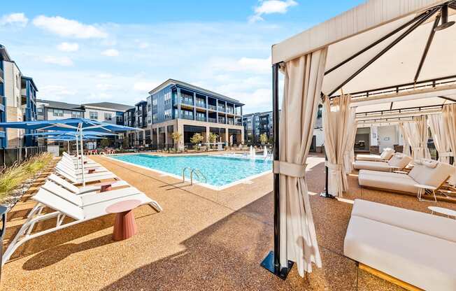 A pool area with sun loungers and a cabanas at Preston Ridge Apartments in Cary, NC.