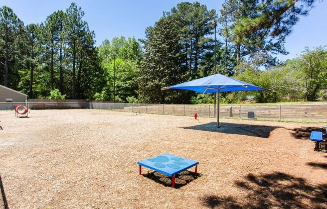 A blue umbrella is in a yard with a blue table and a red fire hydrant.