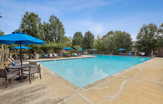 our resort style swimming pool is surrounded by patio furniture and umbrellas