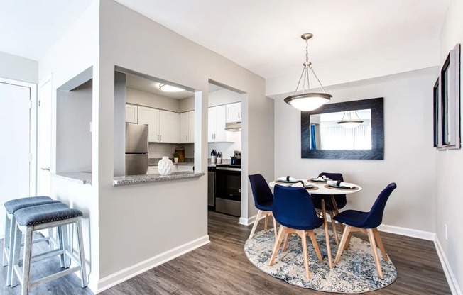 A kitchen with a bar stool and a dining table with chairs.