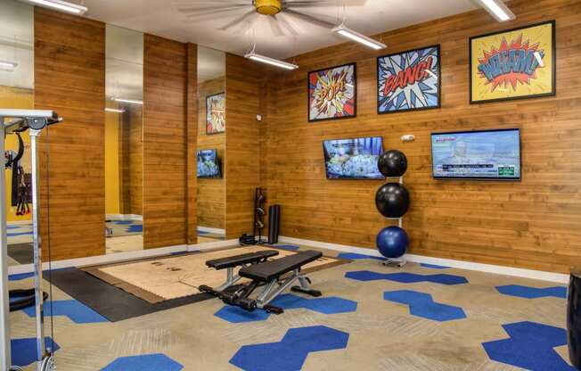 Community Fitness Center Gym with Cardio and Weight Machines, Yoga Balls and Mirrors. The walls are lined with a wooden shiplap look. 