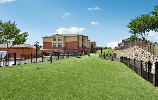 A grassy area in front of a building with a black fence.