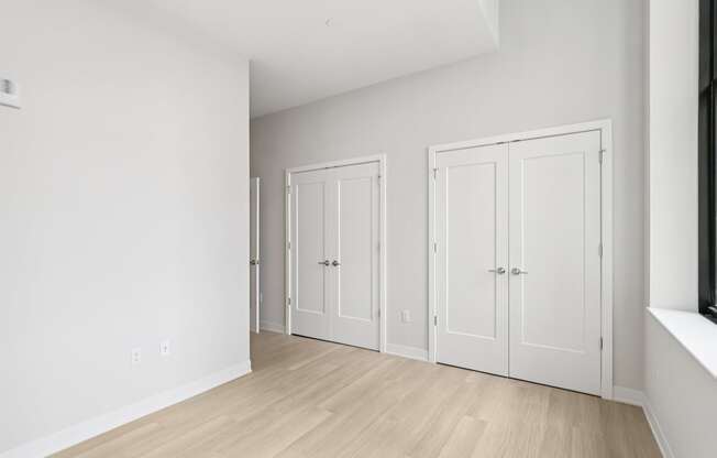 Three white doors are in a room with wood floors.