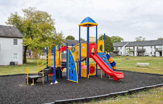 A playground with a red slide and a blue and yellow structure.