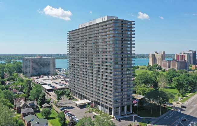 Image of exterior of building. Building stands 30 stories tall, blue skies and green trees surrounding.