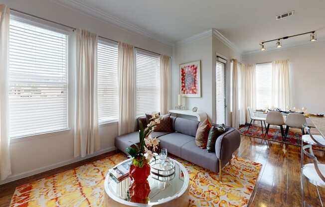 a living area with a couch coffee table and a dining room table in the background