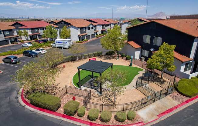 A park area with a gazebo and a fence in front of apartment buildings.