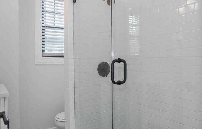 a white bathroom with a glass shower door