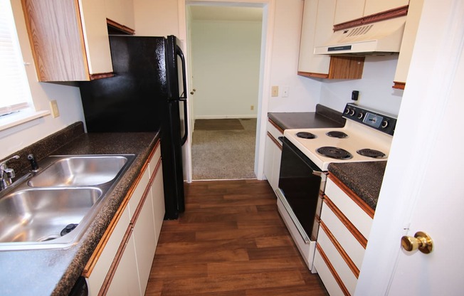 A kitchen with a black fridge and stove top oven.