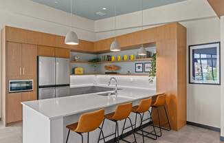 A modern kitchen with a white countertop and orange chairs.