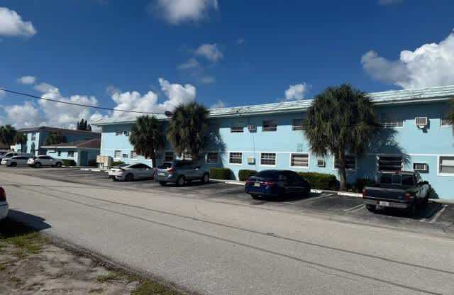 A street with cars parked and a blue building in the background.