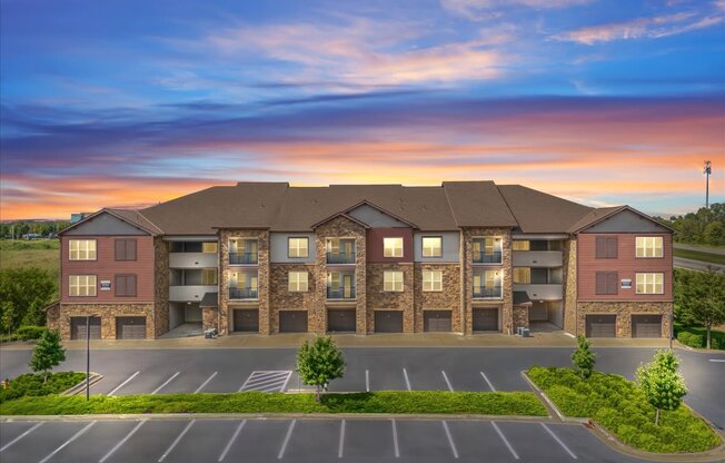 A large apartment complex with a parking lot in front.