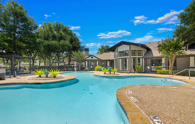 A large swimming pool in front of a building with trees around it.