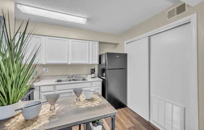 A kitchen with a black refrigerator and white cabinets.