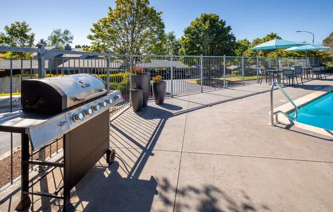 the clubhouse has a grill and a pool with umbrellas