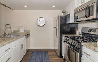 A kitchen with a black refrigerator and stove top oven.
