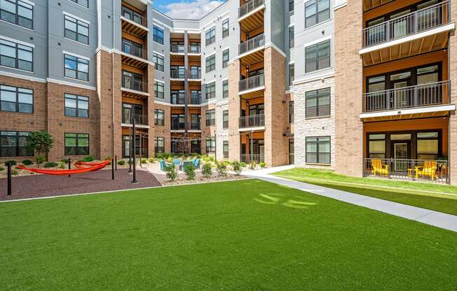 A modern apartment complex with a green lawn in the foreground.