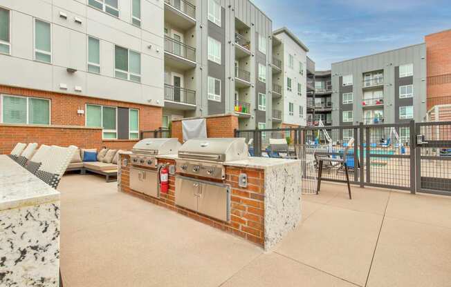 an outdoor patio with a barbecue grill and a pool in front of an apartment building