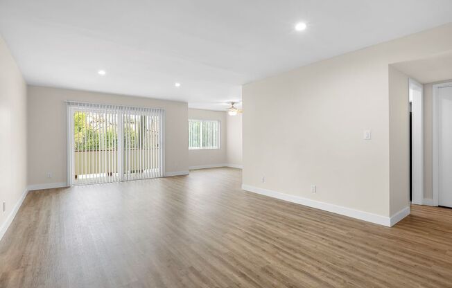A spacious room with wooden flooring and white walls.