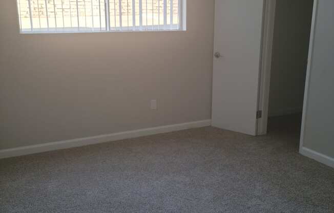 Bedroom with a large window at La Mesa Village Apartments in La Mesa, California..