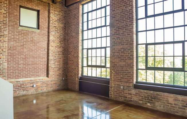 A room with a ceiling fan and large windows.