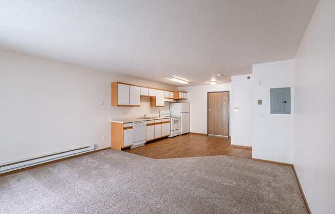 the living room and kitchen of an apartment with a carpeted floor. Fargo, ND Eagle Run Apartments