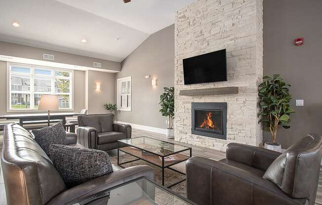 A community room with a fireplace and a television at Strathmore Apartment Homes, West Des Moines, IA