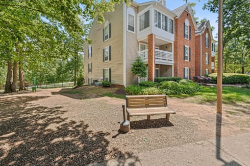 A bench sits in front of a building with a brick chimney.