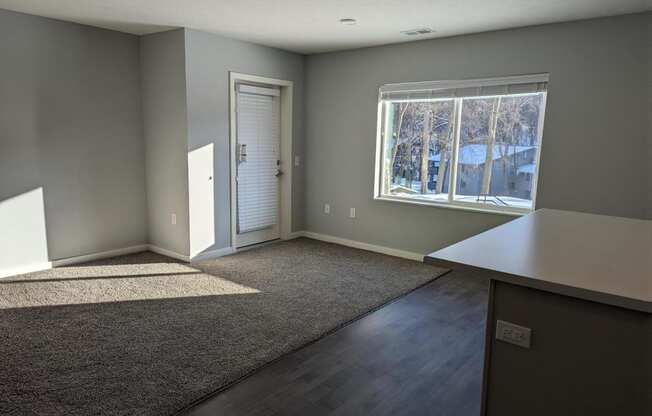 an empty living room with gray walls and a window