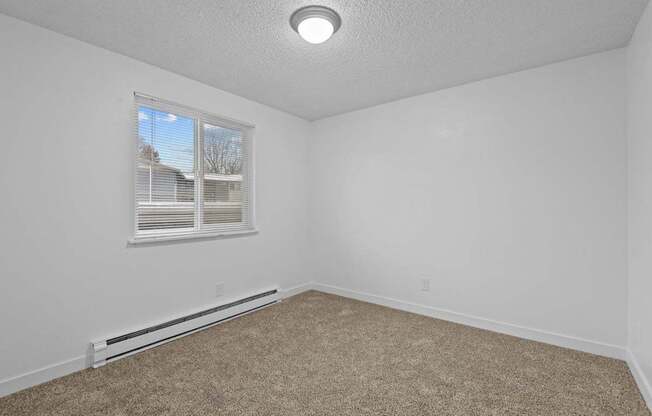 A room with a window and carpeted floor.