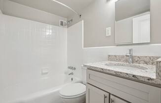 A white bathroom with a tub, toilet and sink.