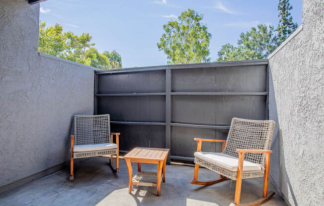 a patio with two chairs and a coffee table