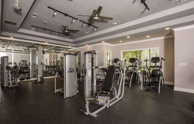 A gym with a variety of equipment including treadmills, weights, and exercise machines.