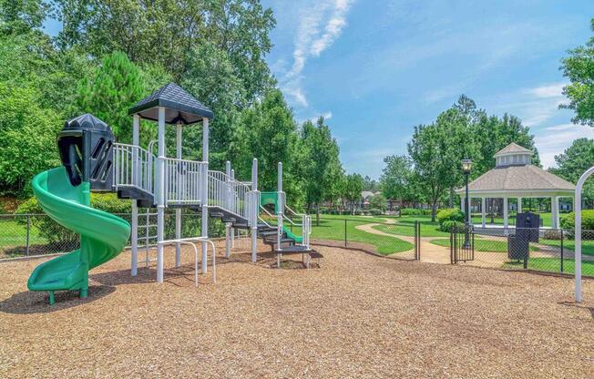 a playground with a slide and a gazebo in a park