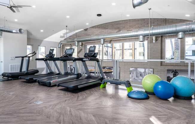 a gym with treadmills and exercise balls on the floor