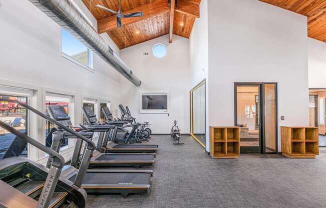 A gym with treadmills, exercise bikes, and a television.