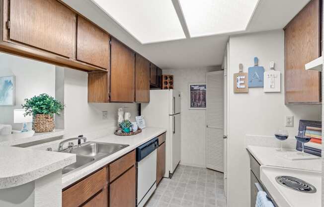 a kitchen with white appliances and wooden cabinets at Pebblebrook, Overland Park