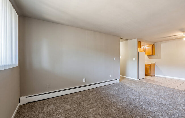 an empty living room with a large window and carpet