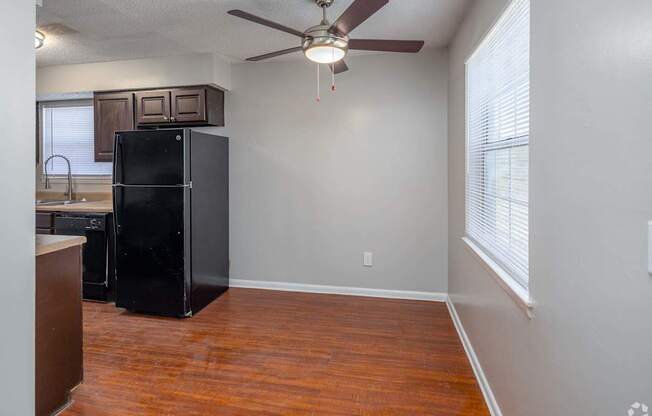 a kitchen with a black refrigerator and a ceiling fan