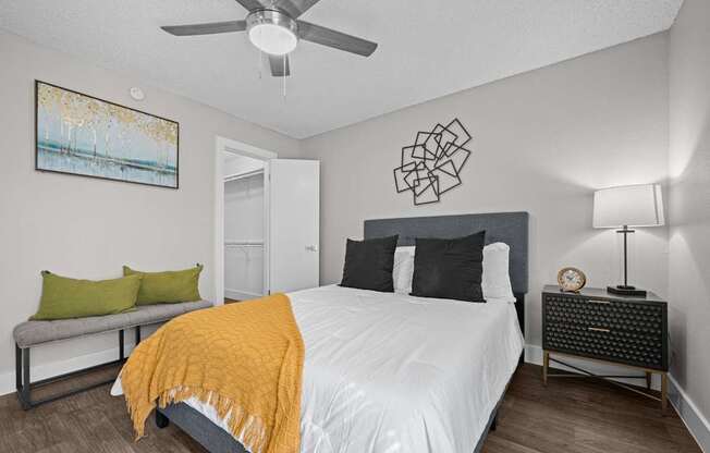 A bedroom with a bed, nightstand, and a painting on the wall.