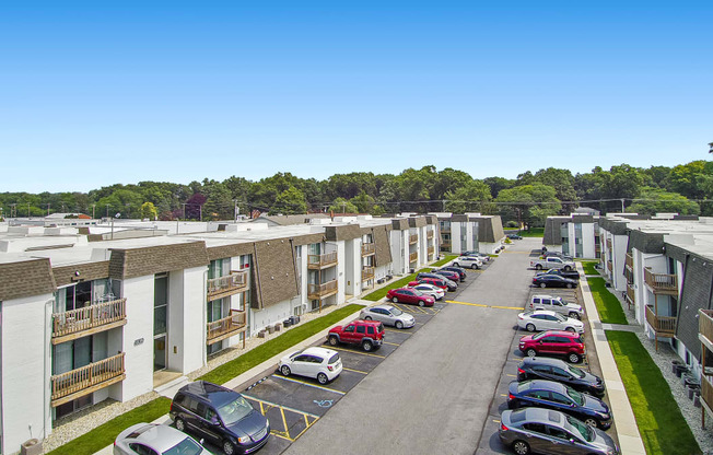 an aerial view of an apartment complex with cars parked on the side of the road