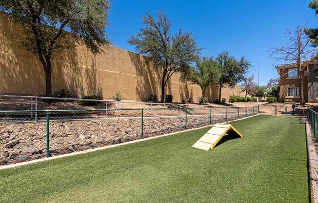 A playground with a yellow slide and green grass.