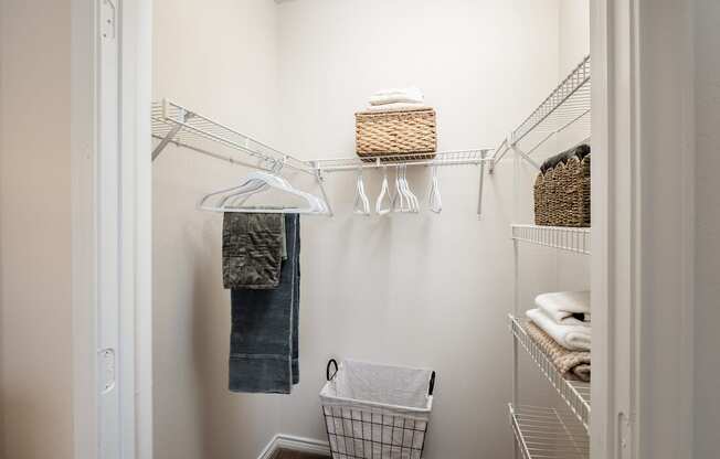 A white laundry room with a basket on the wall and clothes hanging.
