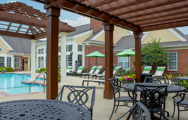 a patio with tables and chairs and a pool in the background