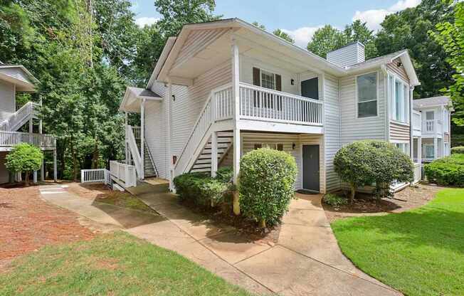 A white two-story house with a balcony and a staircase leading to the second floor.